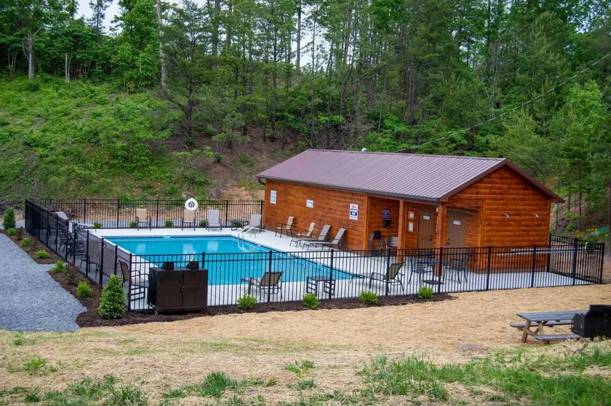 This image captures a sparkling swimming pool in front of a log cabin, surrounded by lush greenery and lounge chairs. The inviting pool area hints at both relaxation and active fun for families, while the greenery and log construction connect to the resort's mountain setting.