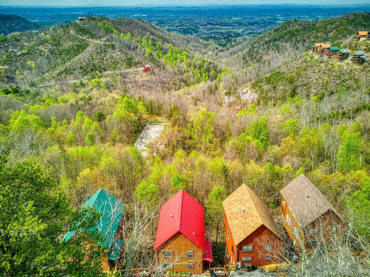 Colorful cabins scattered across lush greenery with a dramatic mountainous backdrop, perfectly evoking the vibrant setting of Eagle Crest Resort and its proximity to outdoor exploration and local attractions.