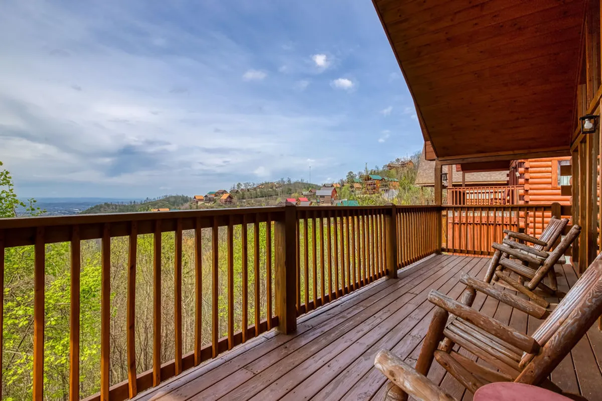 An inviting wooden deck with classic rocking chairs overlooking distant hills and an expansive sky. The tranquil setting is perfect for savoring morning coffee or enjoying sunset views together, with the wooden railing and cozy chairs suggesting comfort and togetherness.